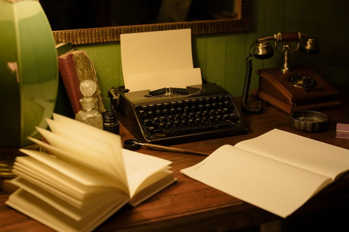 A vintage desk with a typewriter, books and a retro lamp