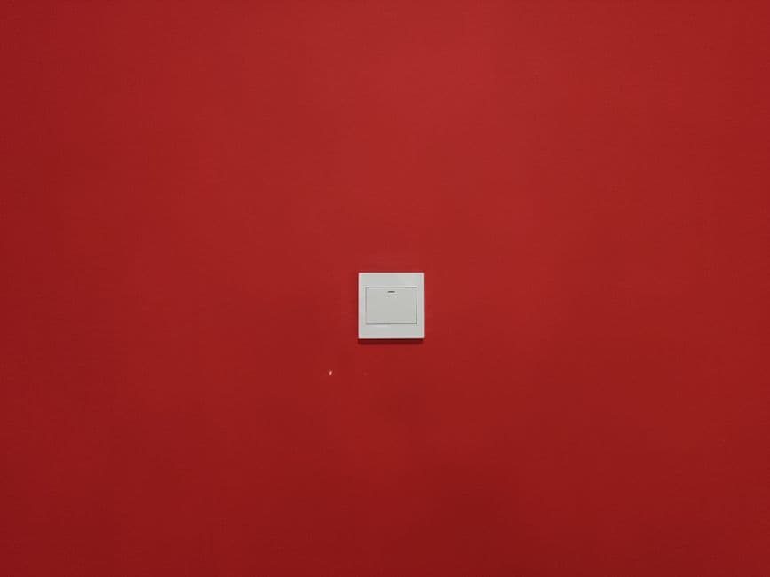 A single light switch on a red wall