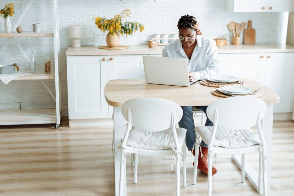 A woman typing on a laptop at a dining table