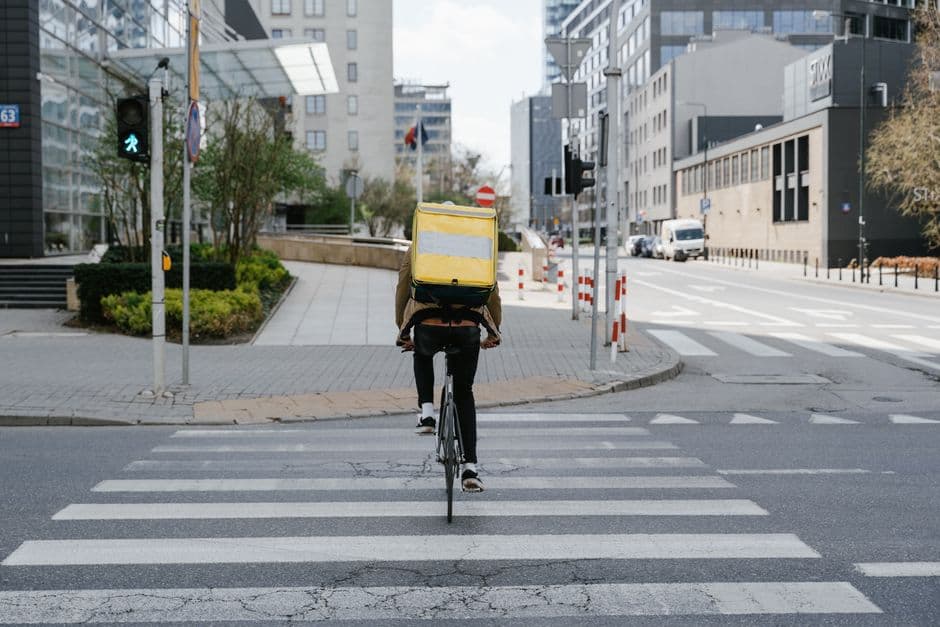 A courier on a bicycle crossing a road