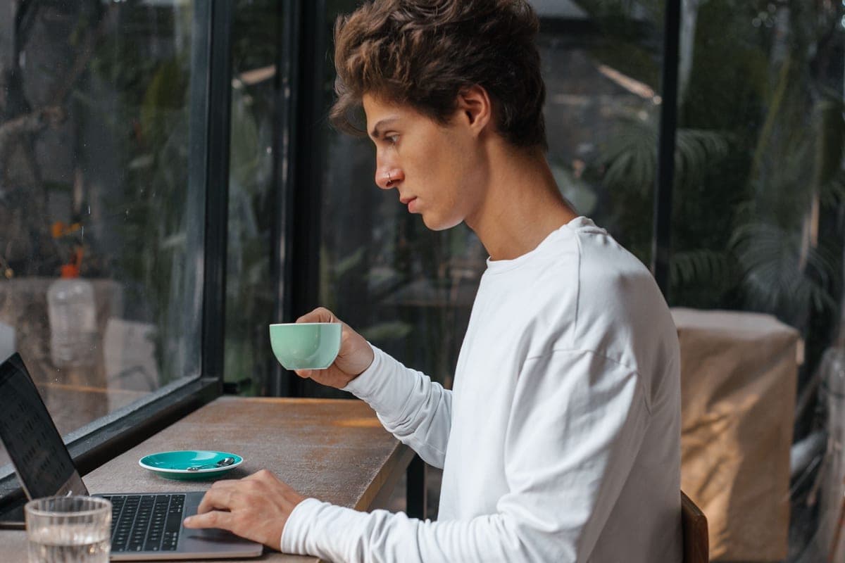 A young adult working on a laptop in a cafe