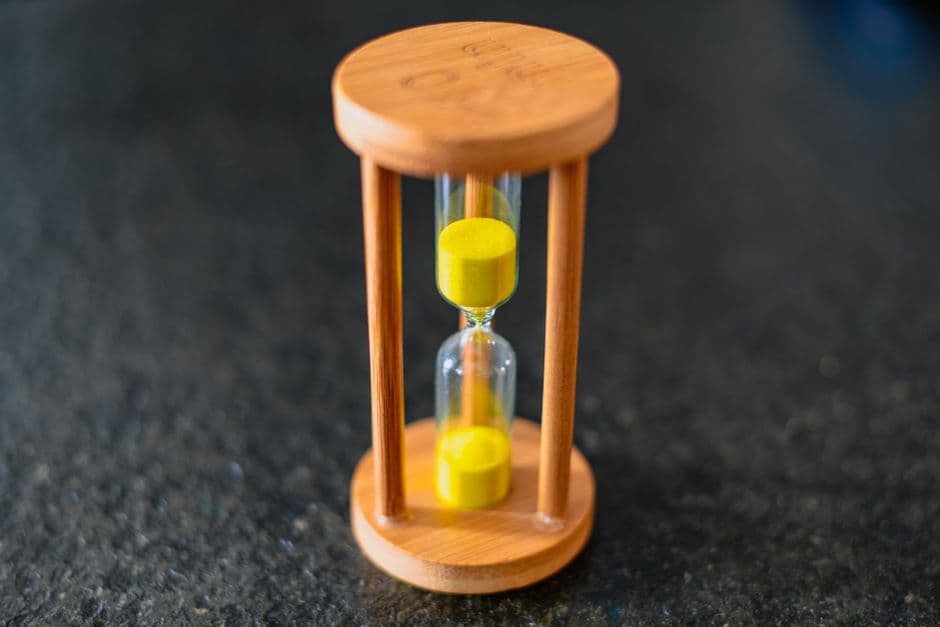 A wooden hourglass with sand running through it