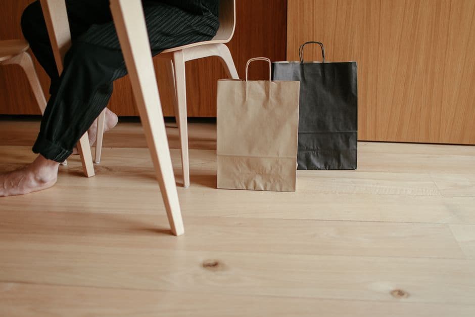Paper shopping bags standing on a wooden floor beside a table