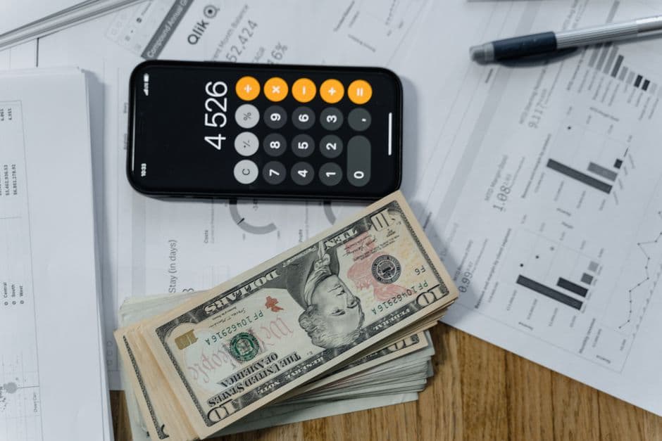 A calculator, cash and financial documents on a desk