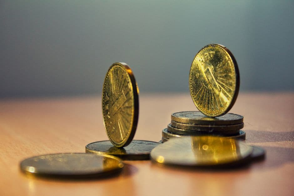 Two coins standing on edge on small stacks of coins on a wooden table