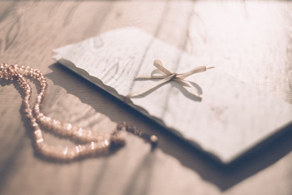 An envelope tied with a ribbon on a sunlit wooden table