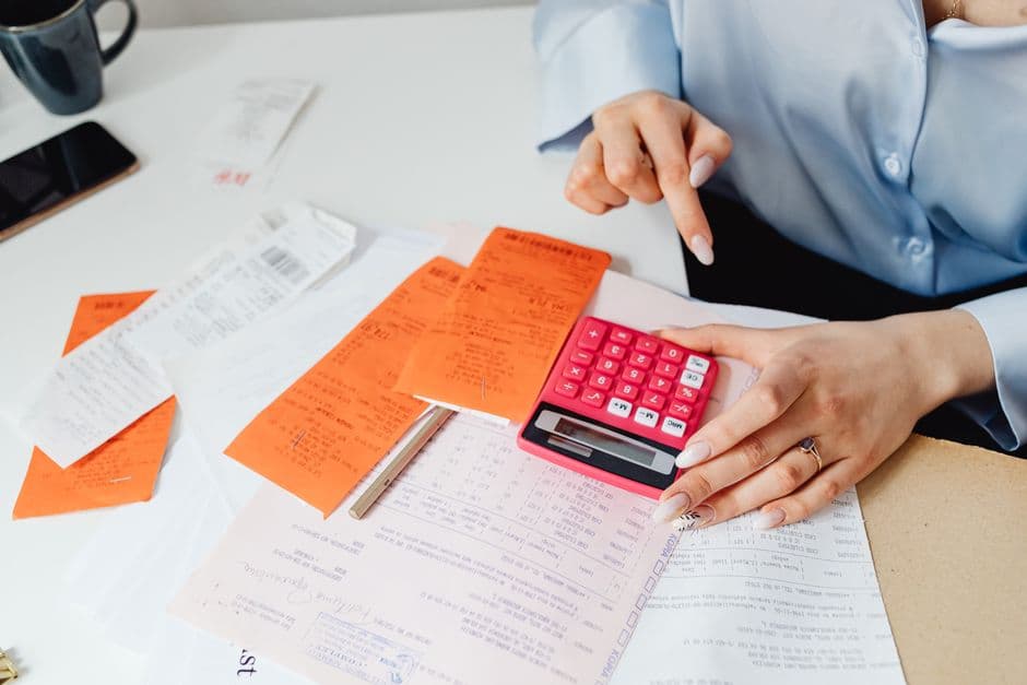 A hand holding a small calculator over a desk