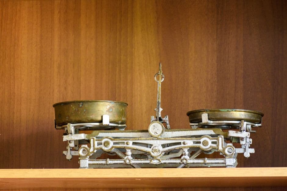 A brass balance scale on a wooden shelf