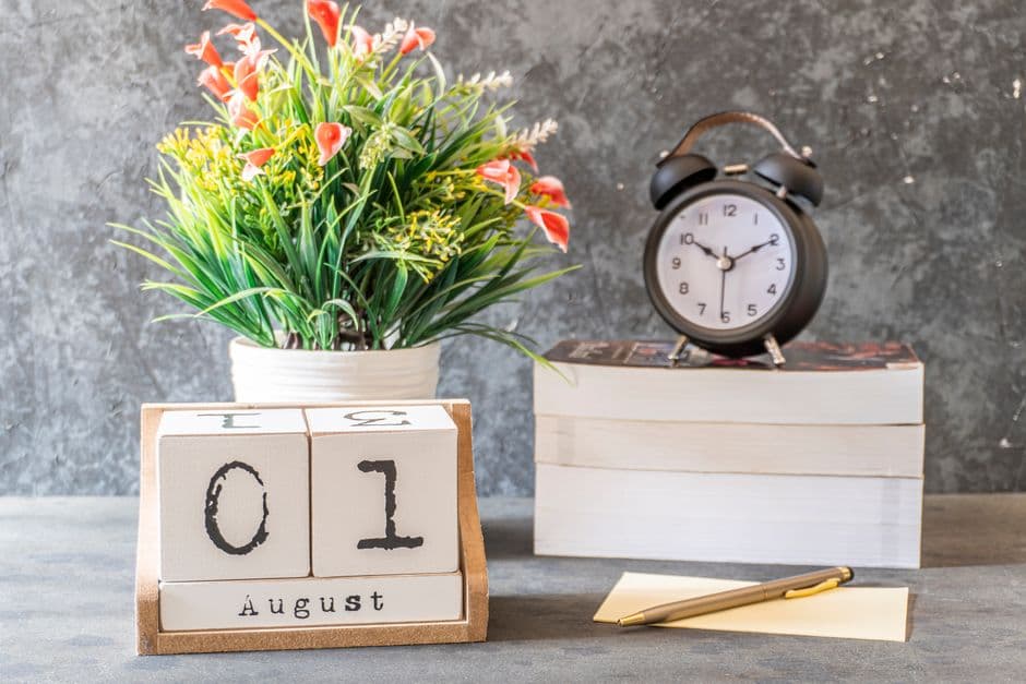 A desk calendar and clock beside books on a table