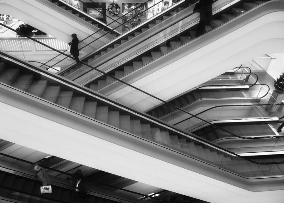 Intersecting escalators inside a building, in black and white