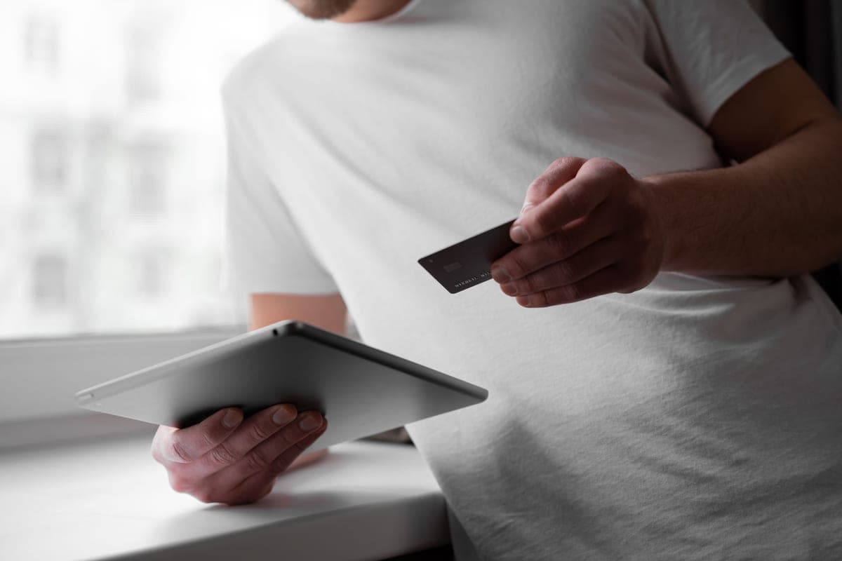A person using a tablet and a card to make an online purchase