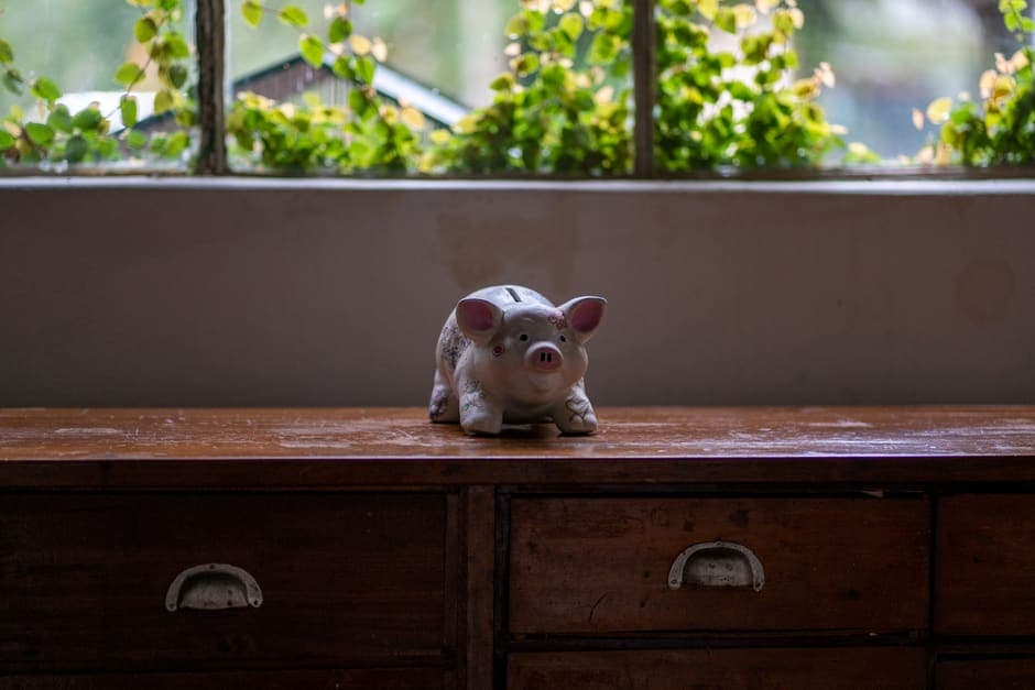 A piggy bank standing on a wooden dresser