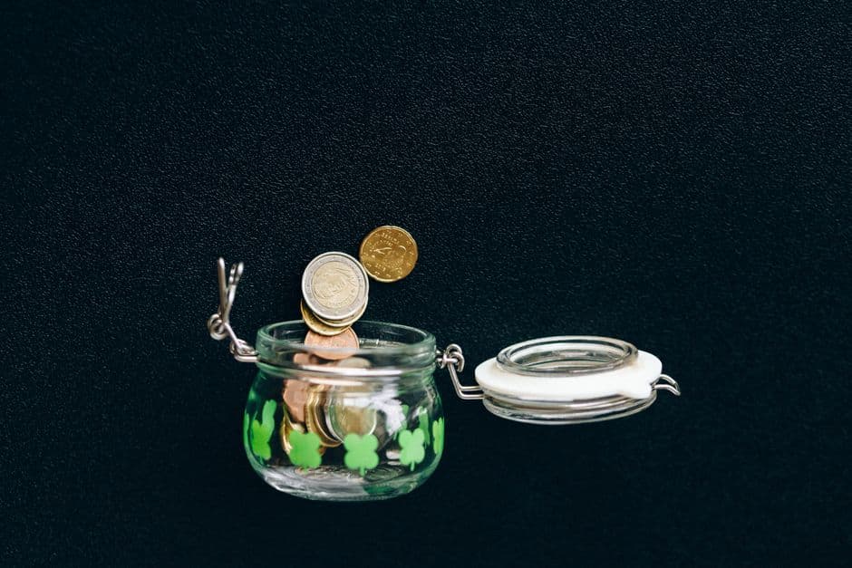 Coins falling into a glass jar