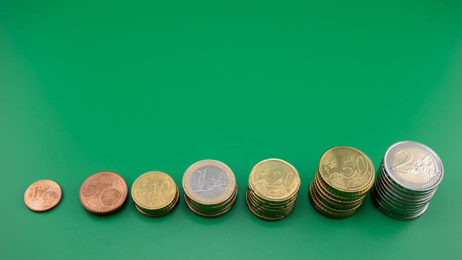 Euro coins stacked in rising columns on a green surface