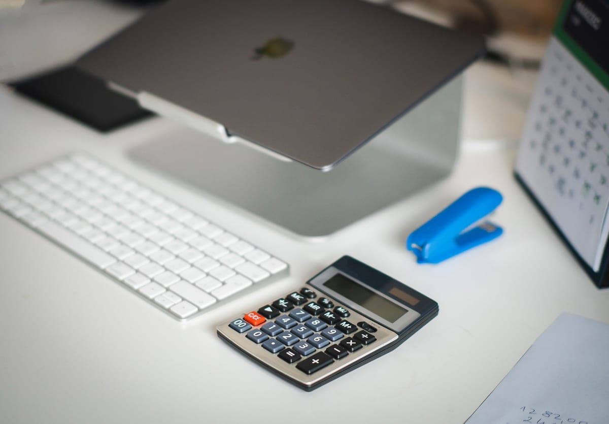 A desk with a laptop, a calculator and a paper calendar