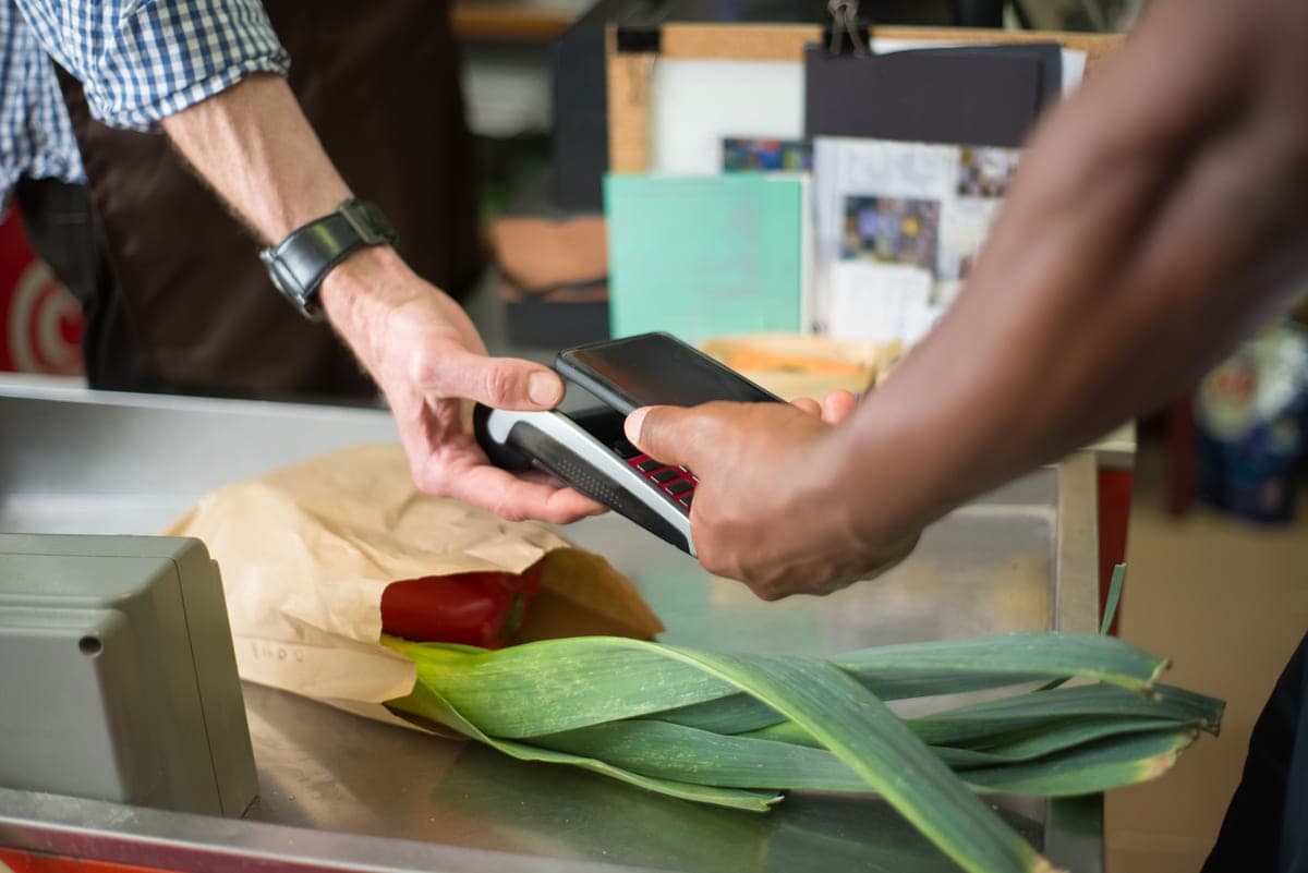 A shopper making a contactless payment at a grocery store checkout counter