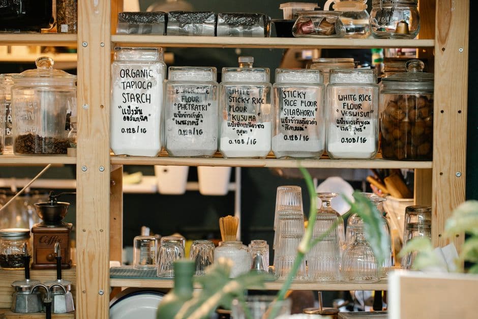Glass jars of dry food arranged on a wooden pantry shelf