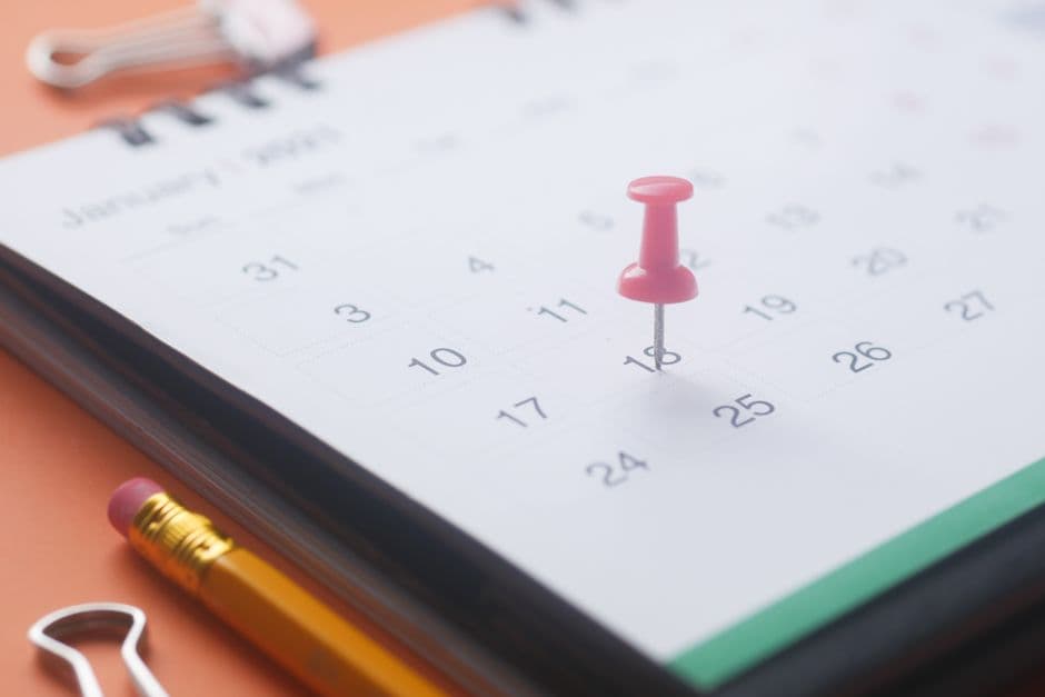 A calendar page marked with a push pin, pencil and binder clip
